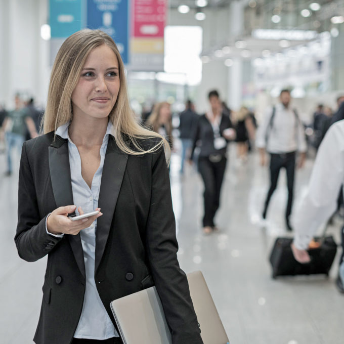 junge Frau auf einer Job-Messe hält Smartphone in der Hand