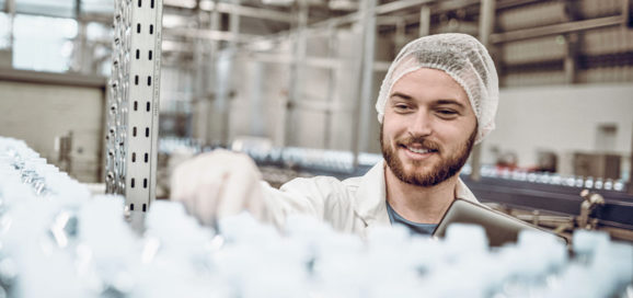 Ein junger Mann mit Haarnetz in einer Fabrik