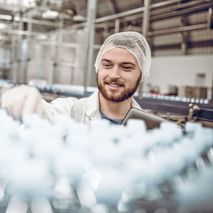 Ein junger Mann mit Haarnetz in einer Fabrik