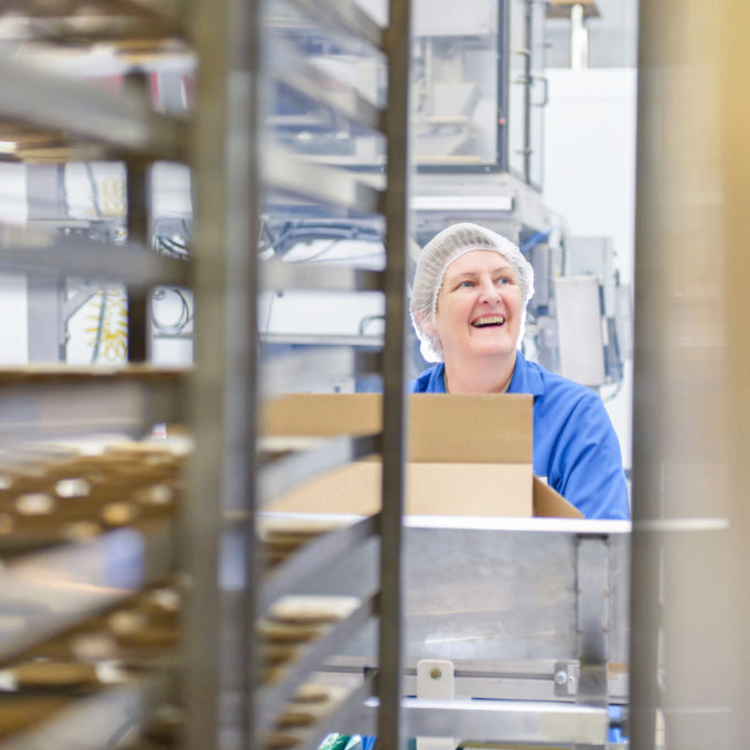 Eine lachende, ältere Frau in einer Lebensmittel-Fabrik