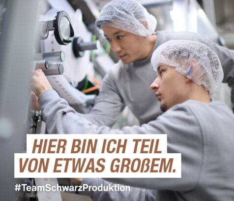 zwei Azubis mit Haarnetzen an einer Maschine