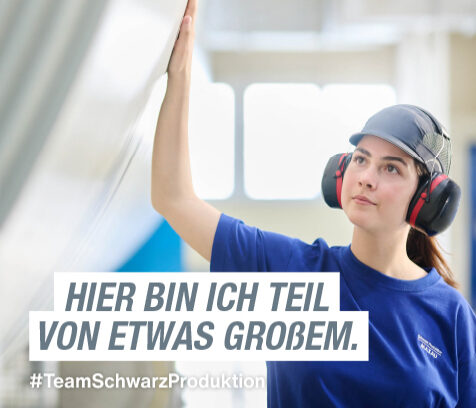 Azubi mit Gehörschutz neben einer großen Papierrolle