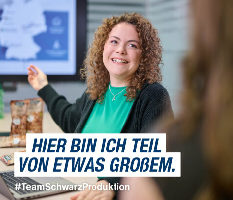 Azubi mit Locken und grünem Shirt in einem Meetingraum