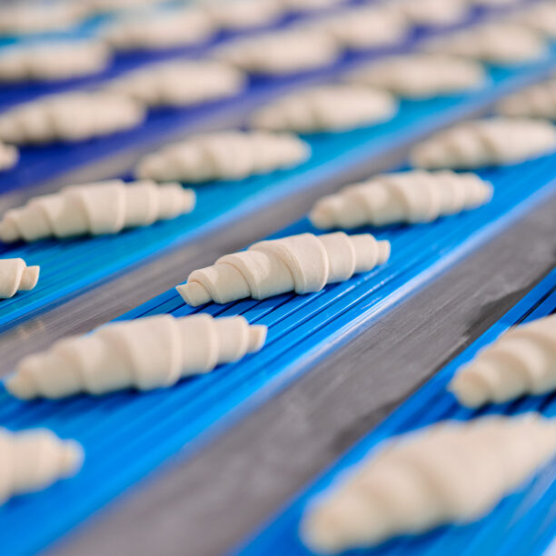 ungebackene Croissants auf blauen Fließbändern