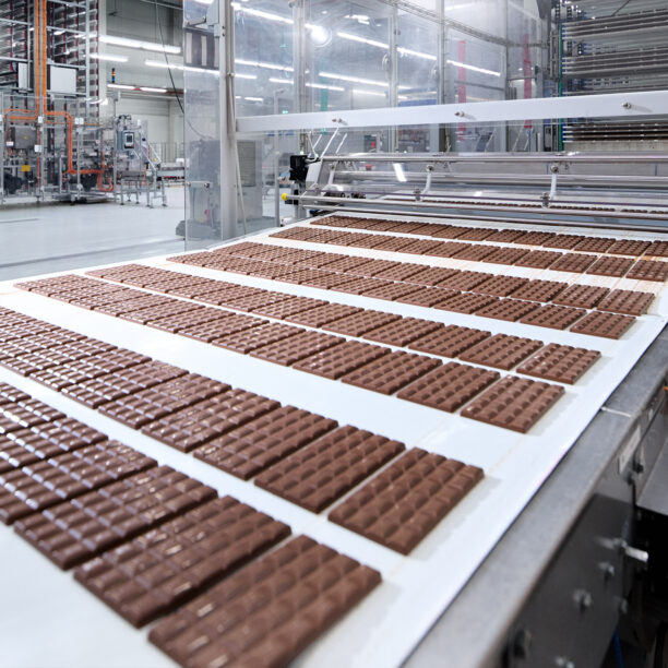 viele Tafeln Schokolade auf einem Fließband in einer Produktionshalle
